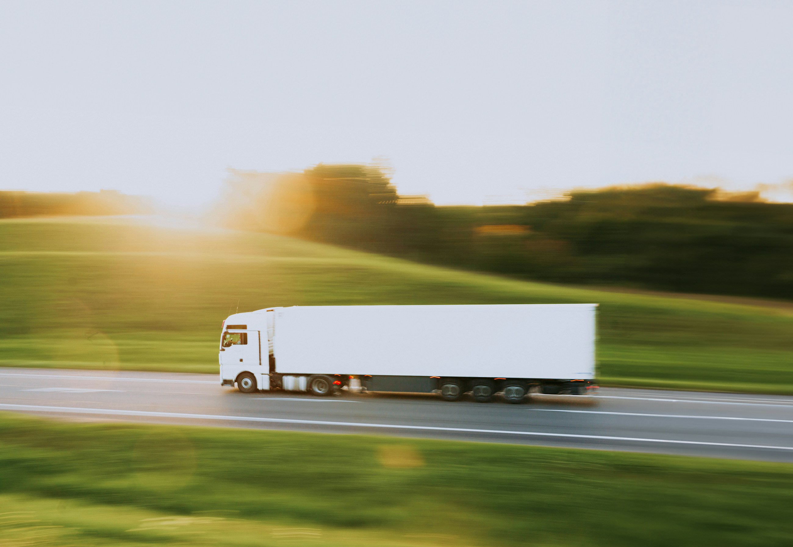 White semi-truck traveling along a rural road
