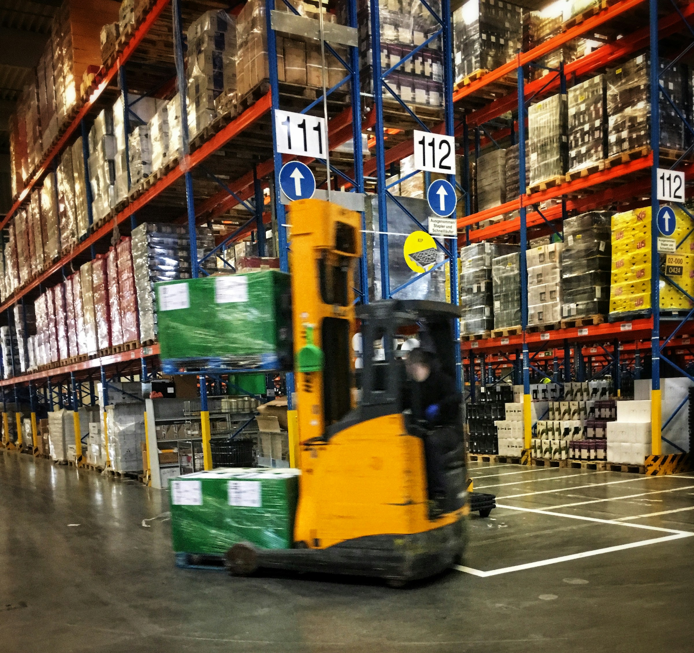 Forklift moving a pallet through warehouse storage aisles